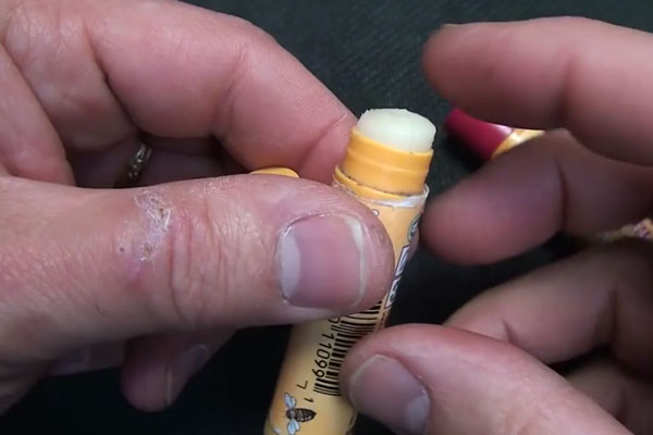 Chapped human hands holding chapstick