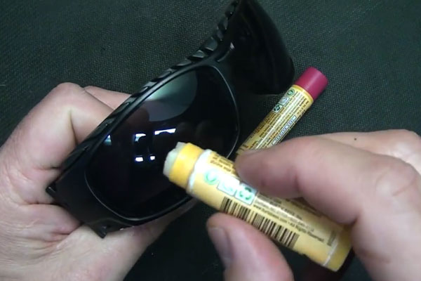 Human hands rubbing chapstick on sunglasses