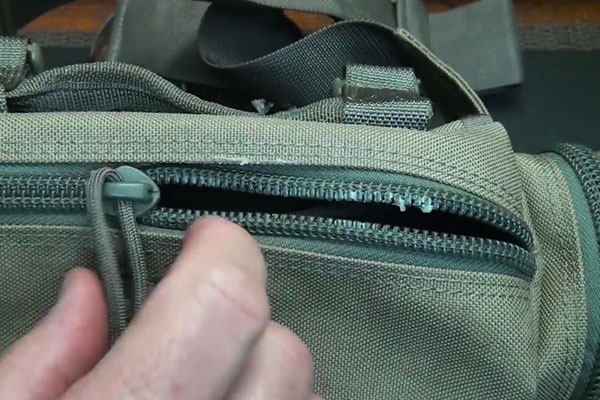 Hands unzipping a zipper on a green bag