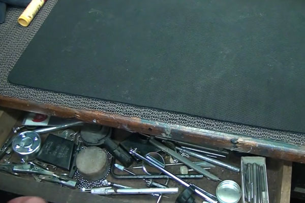 Wooden drawer in table with pens, tools, and candles