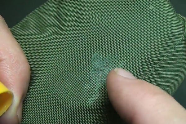 Hands pointing at a pinprick in green bag