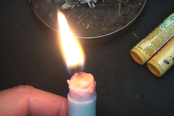 Human hand holding a chapstick on fire