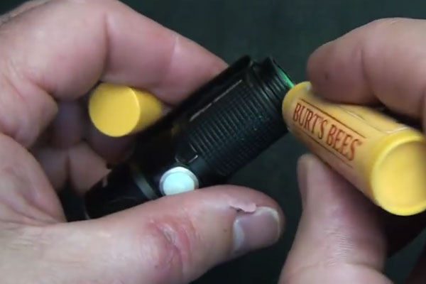 Human hands rubbing chapstick on a flashlight