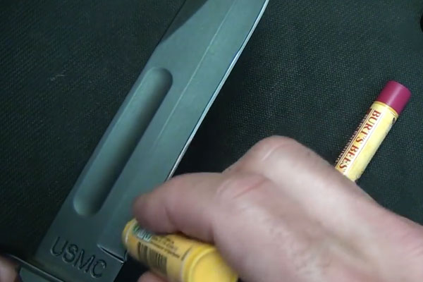 Human hands rubbing chapstick on a knife