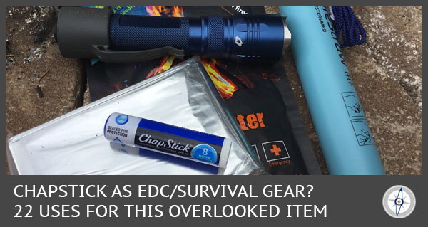 Chapstick, mylar blanket, purifying straw, fire starter, and flashlight laying on the ground