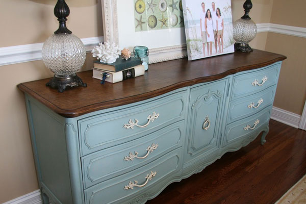 Dresser with lamps, books, and pictures on top of it