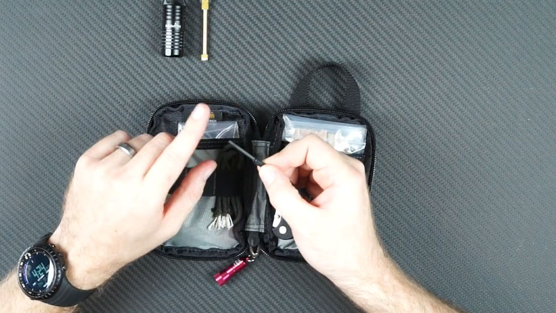 two hands holding ferro rod over kit on table