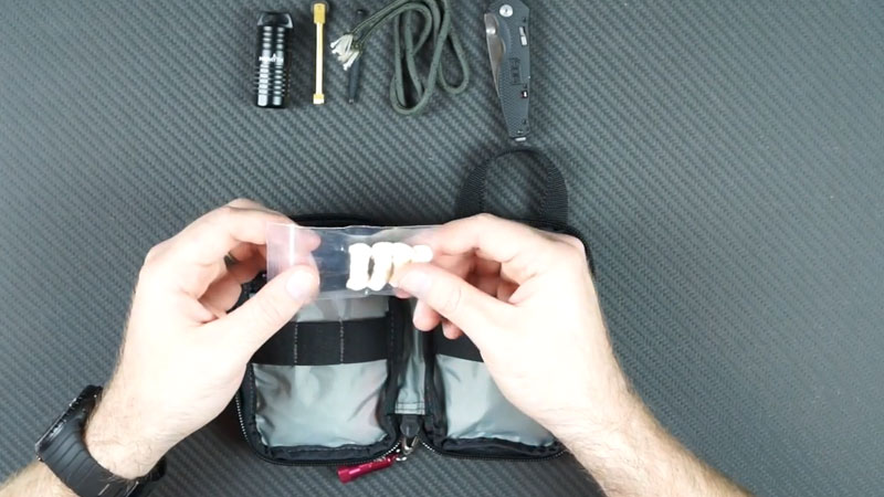 tinder-quick fire tabs in a bag held by two hands over a fire starter kit