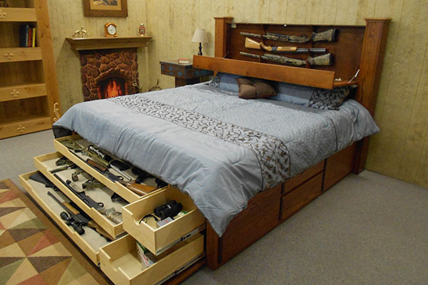 Bed with open drawers containing guns
