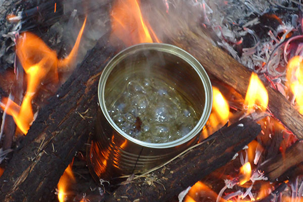 Boiling water on a fire inside of a tin can