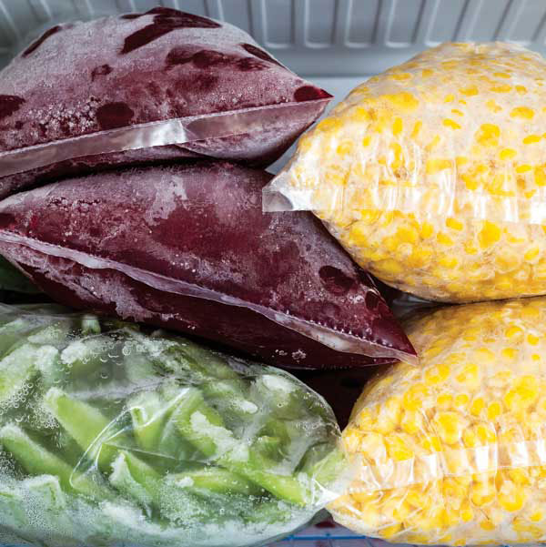 Bagged corn, beans and vegetables frozen in a freezer