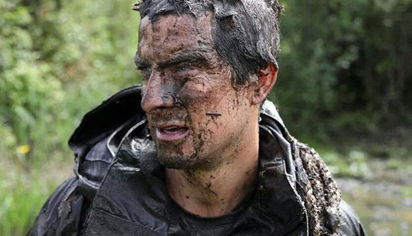 Bear Grylls with mud on his face in the woods