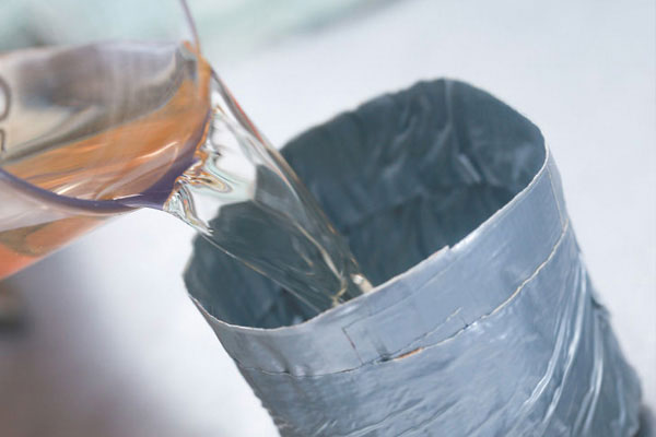 Glass cup pouring water into a cup made from duct tape