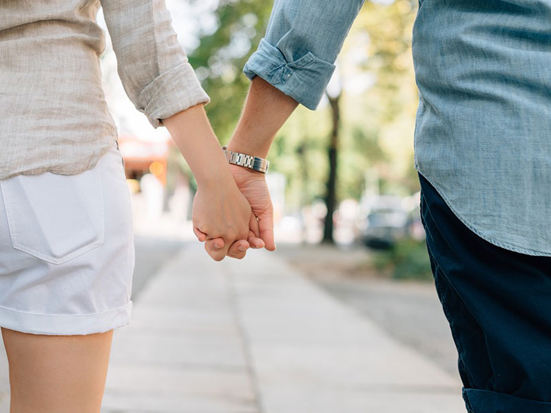 couple holding hands walking down the street