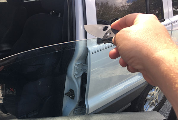 Human hand using a car window to sharpen a knife