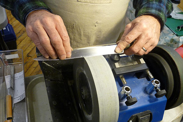 Person sharpening a knife blade on a grinder