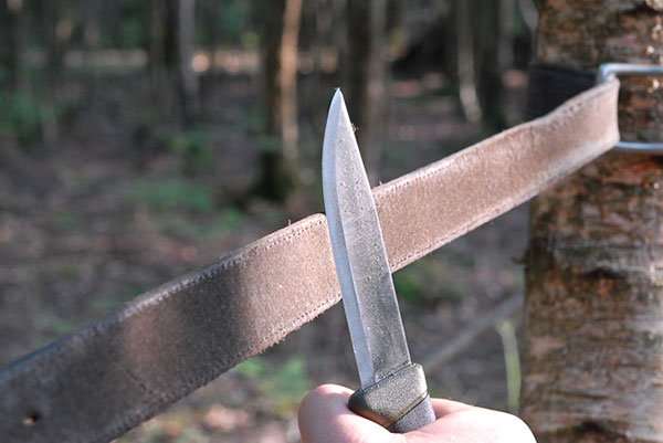 Person sharpening a knife on a leather strop