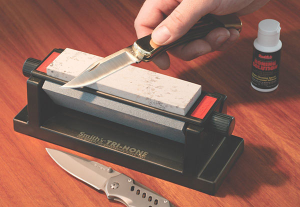 Hand using wetstone to sharpen a knife blade