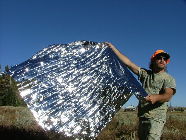 man unfolding an emergency blanket