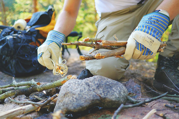 Person in gloves preparing a fire with sticks