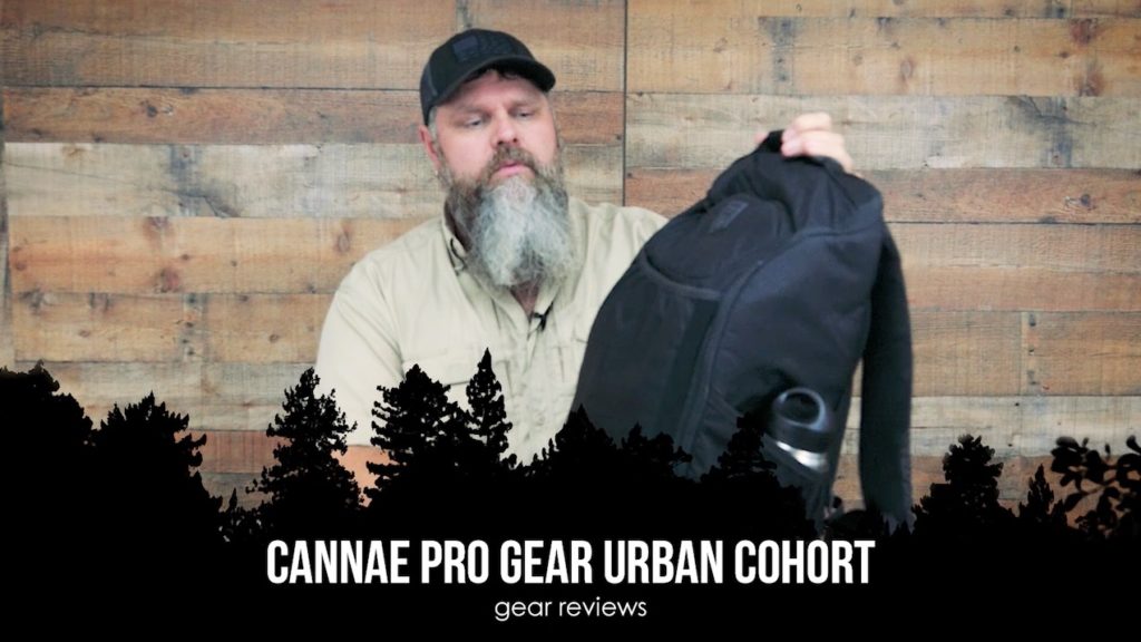 Man holding a black Cannae Pro Gear Urban Cohort backpack
