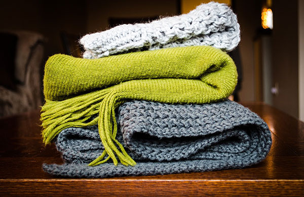 Blue, green, and white blankets stacked on a table