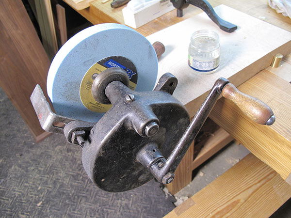 hand powered grinding wheel attached to a wood work bench