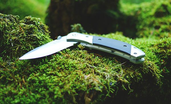 An opened knife laying on some moss