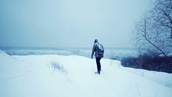 man walking through a snow covered landscape