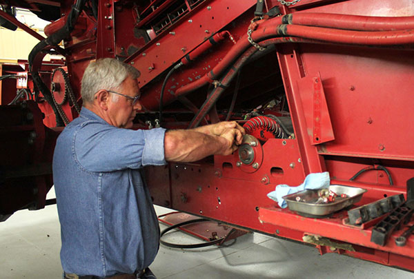 older man fixing a red diesel tractor