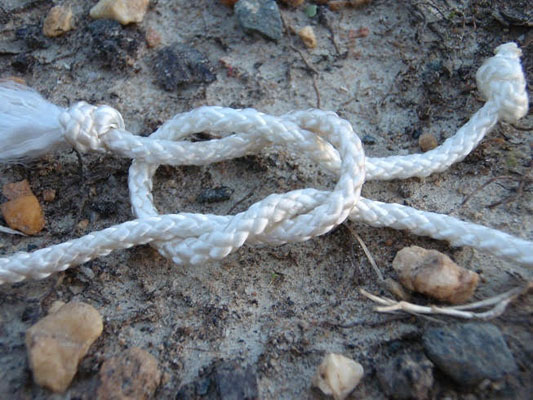 white rope on the ground tied in a square knot